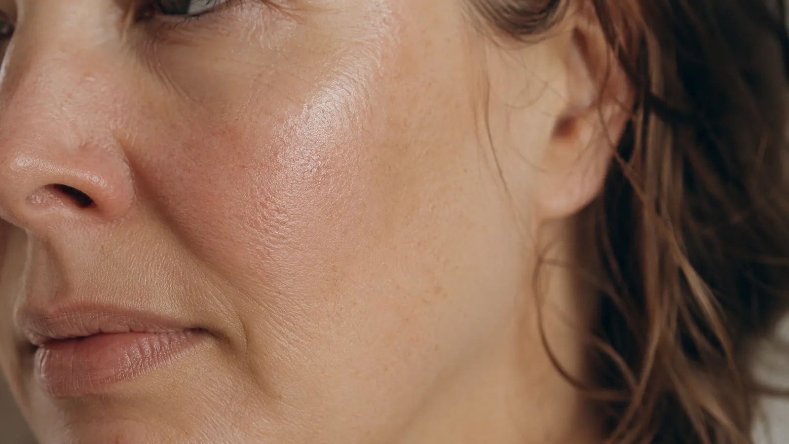 Close-up of smoother, dewy bare skin on a cheek in daylight, no makeup