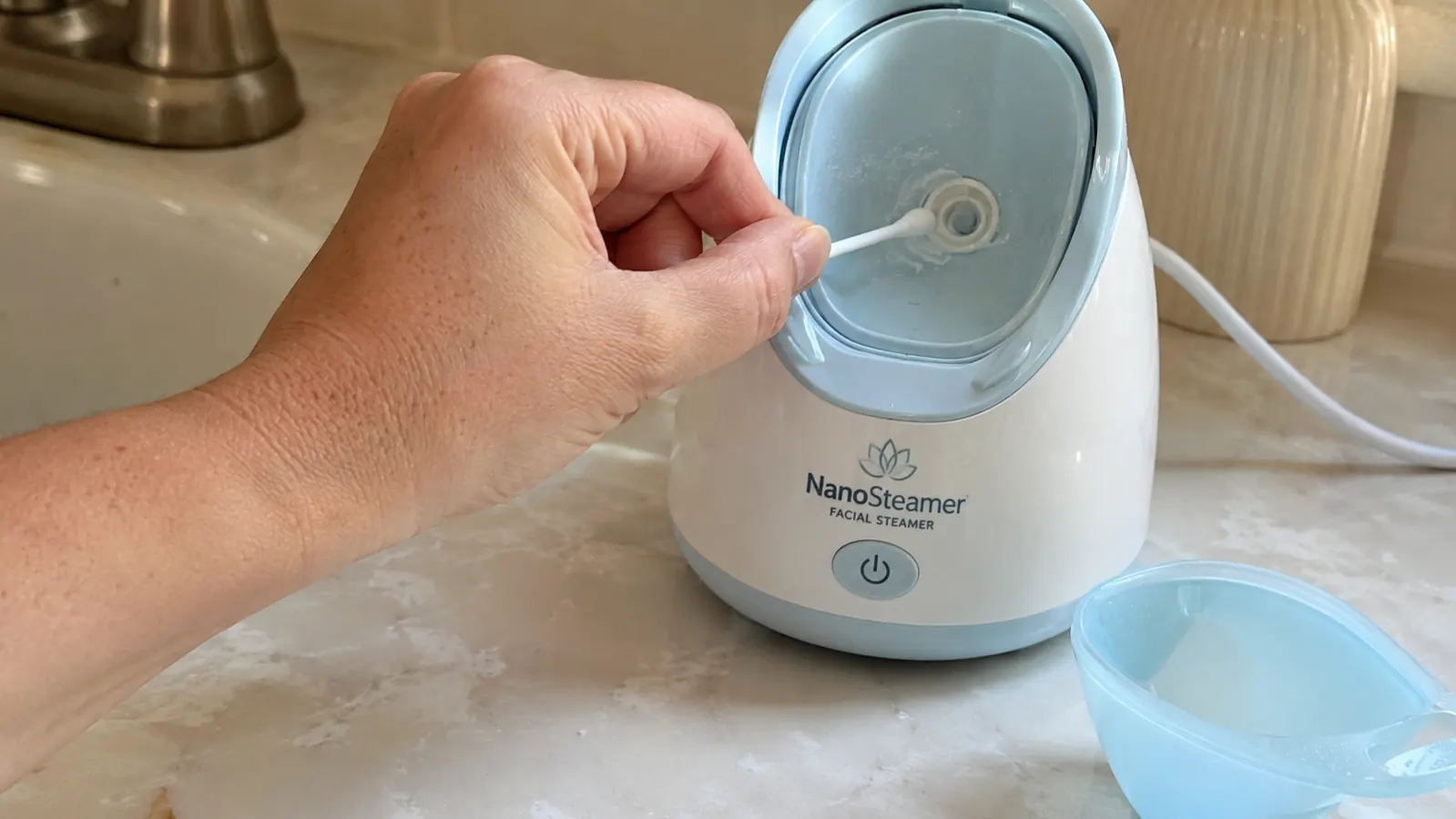 Hand wiping down the inside of the NanoSteamer's water tank with a cotton swab after a session